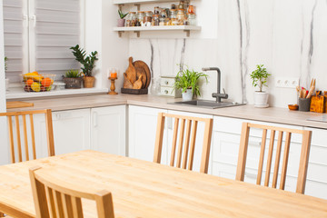 Scandi kitchen intriours with plants, wooden accessories and marble wall.