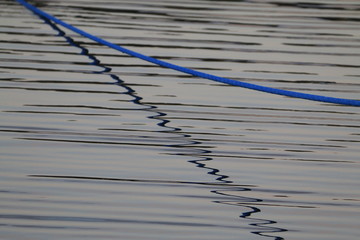 niebieska lina tuż nad tafląlekko  pofalowanej ciemnej wody