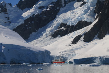 jacht na zimnych wodach okołobiegunowych pokrytych krą z masywnymi górami antarktydy w tle 
