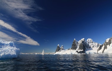 jacht z rozłożonymi żąglami na zimnych wodach okołobiegunowych z antarktydą w tle w...