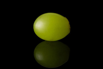 One whole fresh green grape isolated on black glass