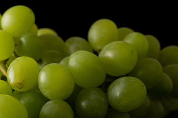 Lot of whole light fresh green grape macro isolated on black glass