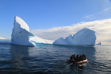 ludzie na łodzi motorowej pomiedzy górami lodowymi wpływający do zatoki u wybrzeży antarktydy - obrazy, fototapety, plakaty