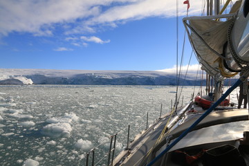 jacht płynący przez zimne wody antarktydy pokryte krą i bryłami lodu