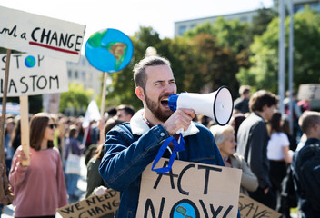Man with placards and amplifier on global strike for climate change, shouting. - obrazy, fototapety, plakaty