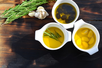 Small bowls of olive oil on a burnt wooden plank