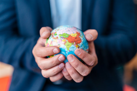 Close-up of businessman holding miniature globe in office