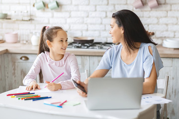 Mother giving attention to daughter while working at home