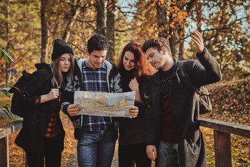 Young tourists, men and women are trying to understand where they are, using a map.