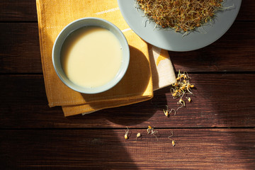 Whole wheat sprouts and wheat milk flatlay composition on wooden table, healthy drink is good for nutrition and face cosmetics, closeup, from above top view, vegan food concept