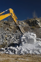 Hydraulic breaker hammer arm destroys a large stone, close-up. Heavy equipment. Mining industry.