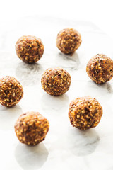 Obraz na płótnie Canvas Energy protein balls with healthy ingredients on marble table. Home made with dates, peanut butter, flax and chia seeds, oats, almond and chocolate drops. Food modern pattern on marble table