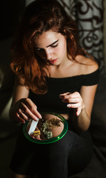 Young woman rolling a joint at home