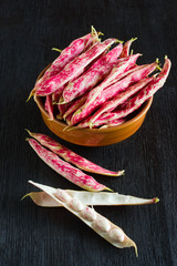 Pink spotty bean pods (Phaseolus) on a wooden black table. Harvest season