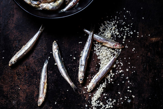 Close-up of fresh anchovies and sea salt on black slate rock