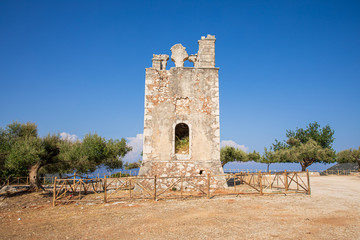 Fototapeta na wymiar Summer sunny day the old bell tower of the Monastery of Argilion in the open territory for tourist visits - Sami, Kefalonia island, Greece.