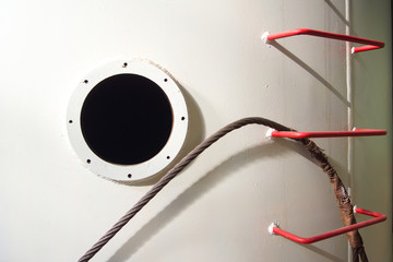 Hatch and red spar-ladder on a white metal wall