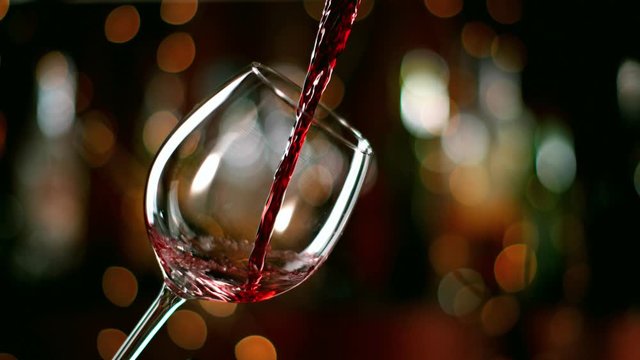 Super slow motion of pouring red wine from bottle into goblet. Filmed on high speed cinema camera 1000fps.