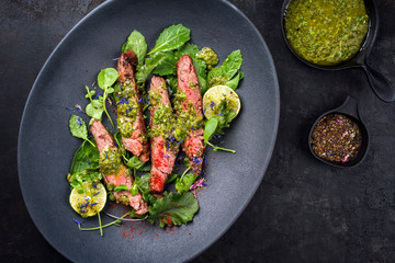 Barbecue wagyu hanging tender steak with chili, lettuce and chimichurri sauce as top view on a...