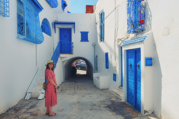 Tourist stands in the courtyard with blue windows and doors with Arabic ornaments. Texture of...