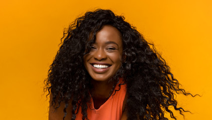 Portrait of happy black curly woman on yellow background