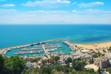 Fototapeta na wymiar Top view of the sea, the port with ships and the road along the coast in Sidi Bou Said, Mediterranean, Tunisia. June, 2019