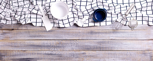 Kitchen utensils, cotton white checkered napkin on old wooden background.
