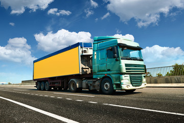 Yellow truck is on highway - business, commercial, cargo transportation concept, clear and blank space on the side view