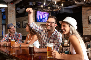 Two couple sitting in beer house and having fun