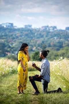 African man proposing to African woman in field