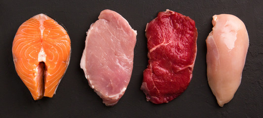 Meat collection on dark background. Beef, pork, chicken, fish isolated on black. Set of natural food. Top view. Flat lay.