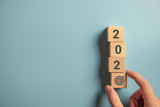 Hand holding wood wooden cubes with New year 2020 and goal icon concept.