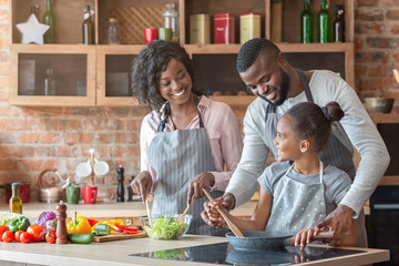 Young parents teaching daughter how to cook