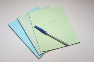  school notebook with pen and paper clips on a white background