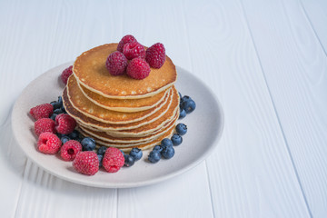 Pancakes with fresh berry on a blue wooden background. Pancakes with fruits. Summer homemade breakfast. Space for text. Blue background.