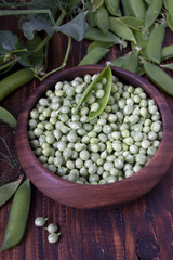 Green peas in a wooden bowl on a brown wooden table against the background  peas