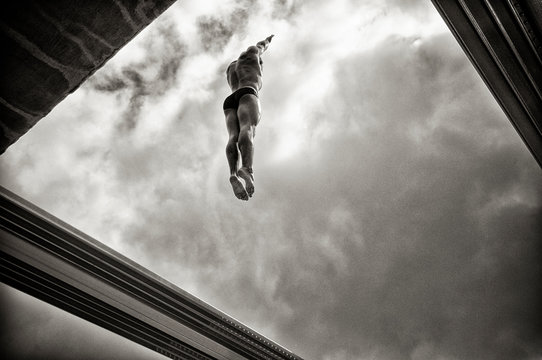 Shirtless man jumping against cloudy sky