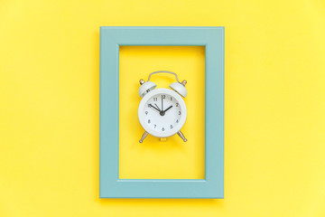 Ringing twin bell vintage alarm clock in blue frame isolated on yellow colorful trendy background....
