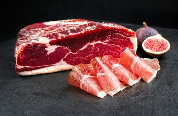 Traditional dry cured and smoked ham with a ripe fig offered on a black board