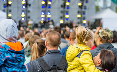 many different people at a concert listening to rock band music open air