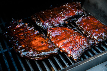 Smoked Barbecue BBQ ribs on the smoker grill charred on the edges and covered in barbecue sauce homemade