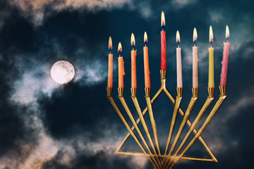 Hanukkah menorah with sparks on full moon in the clouds background
