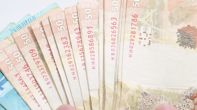 Sliding Brazilian real banknotes like a hand fan. 50 and 100 reais brl. Brazilian money, real notes. Hands sliding money bills.
