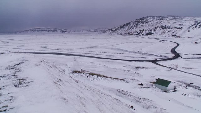 Pan right, cars drive on tundra roadway ion Iceland