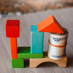 Coins on the top of tower wooden blocks toy, which are removed one block by man hand in finance concept 