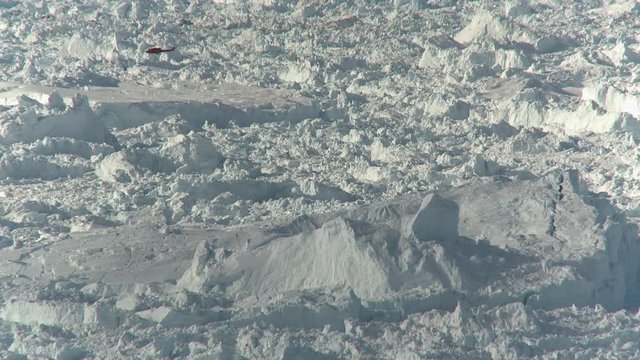 Helicopter flies over glacial landscape, wide