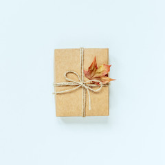 Brown gift box with maple leaf on a white background, top view.