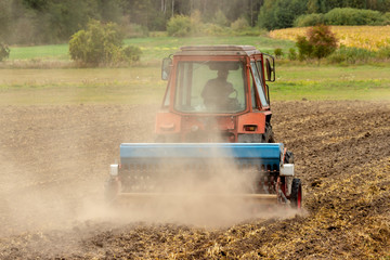 HomA tractor rips the ground in a dusty field.emade goat in the pasture.