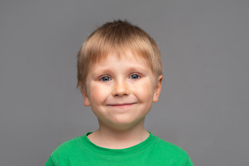 Fototapeta premium Portrait of happy smiling boy in green t-shirt. Attractive kid in studio. Childhood concept.