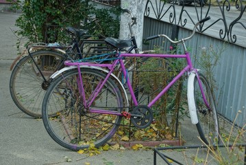 Fototapeta na wymiar an old lilac bike stands on the pavement on a street near a pillar